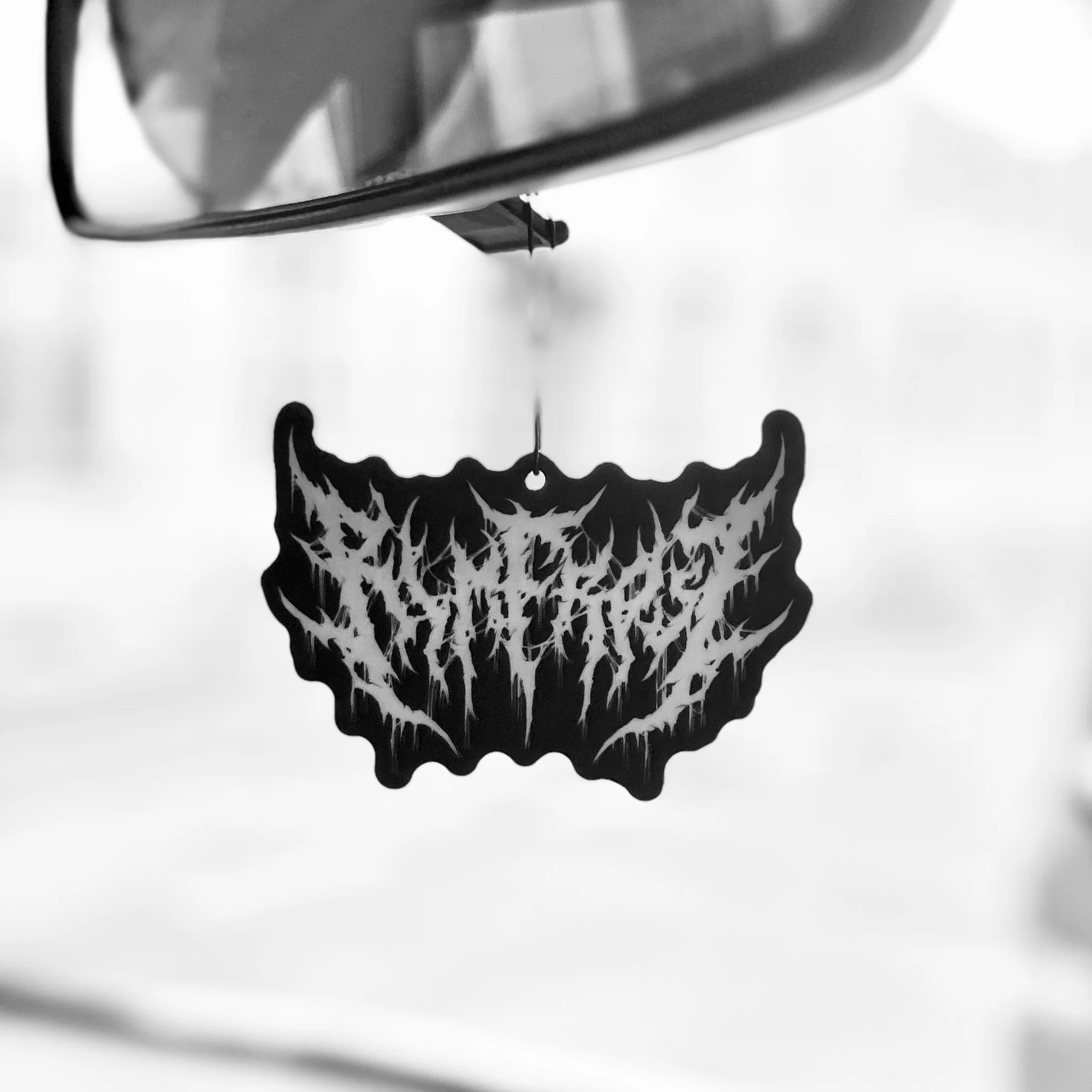 Black and white car air freshener hanging from a car mirror.