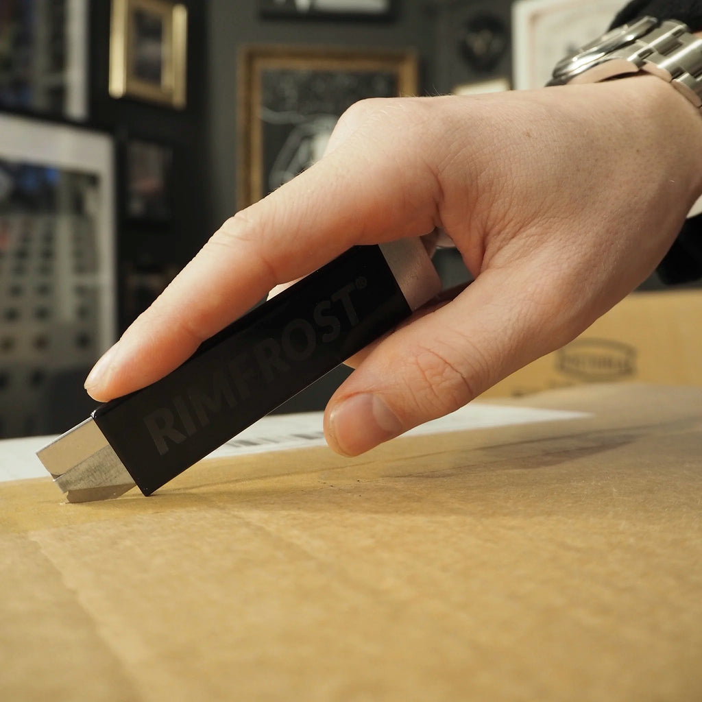 Hand holding a black USB drive labeled 'Silicon Dust' on a wooden surface with a blurred background.